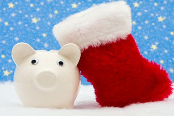 Piggy bank and red stocking sitting on snow and star background