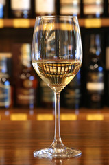 a glass of wine with reflection of bottles