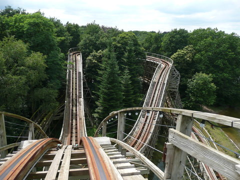 Onboard view of a wooden roller coaster in Efteling amusement park, Netherlands, showing a winding track through the forest
