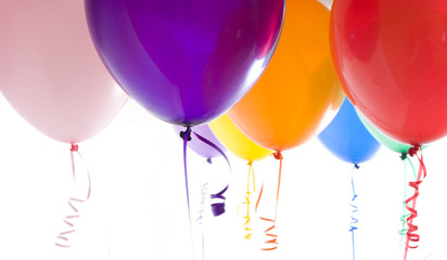 Close up of variety of balloons with ribbons brightly lit