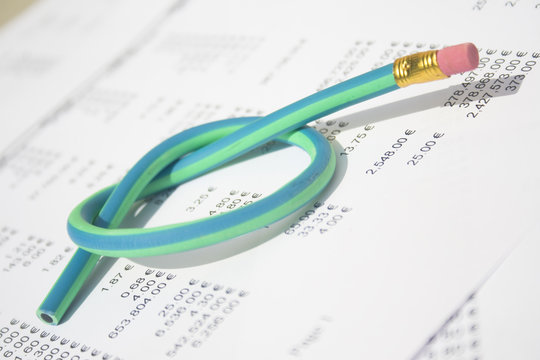 Rubber pencil tied in knot sitting on accounting printout