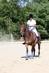 Obraz premium teen on horse in ring at show with dust blowing