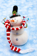 Snowman wearing scarf on blue snowflake background