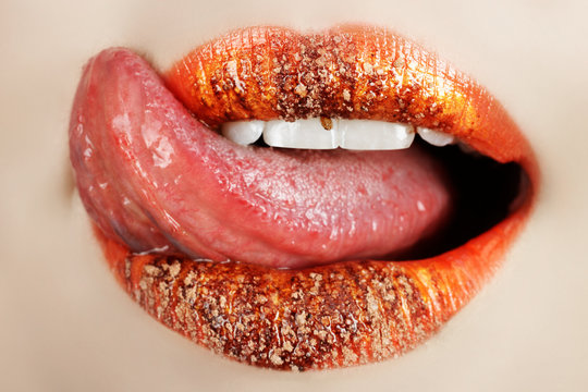 Macro of bright orange make-up on lips with tongue