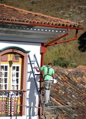 Homme sur une échelle peignant une façade.