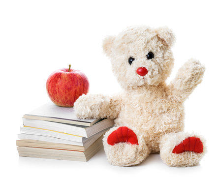 Teddy bear with a heap of books and an apple