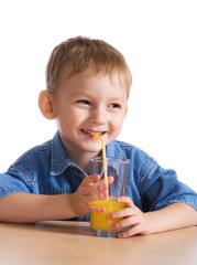 Laughing little boy drinking orange juice..