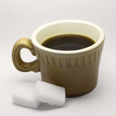 Cup of coffee and two bricks of sugar on a white background