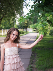 Naklejka premium Girl teenager stands outdoor and touches leaf of maple.