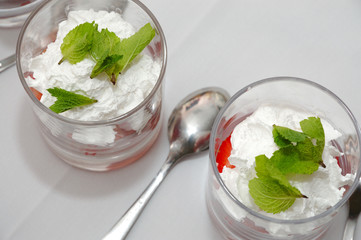 Sliced strawberries with cream and mint in glasses