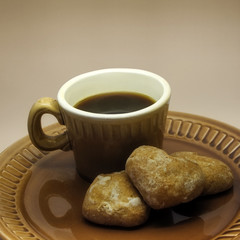 Cup of coffee and three spice-cakes on a ceramic plate