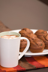 A cup of foaming hot chocolate and chocolate mint muffins