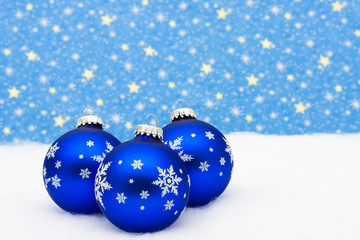 Blue glass Christmas balls on snow with star background