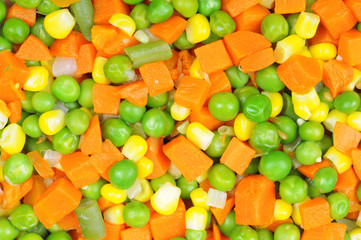 Boiled diced vegetables background with carrot, corn and peas.