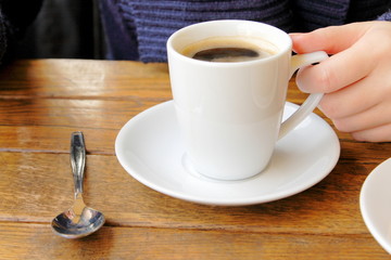 female hand holding a cup of coffee in cafe