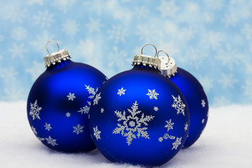 Blue glass Christmas balls on snowflake background