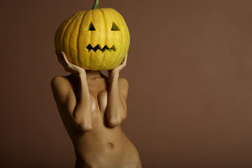 Sexy lady with big pumpkin on head. Surrealstic portrait.
