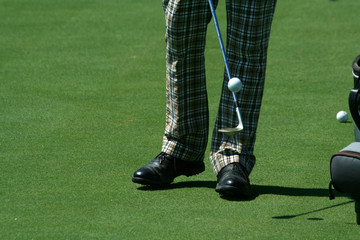 A Golfer juggling a golf ball with retro pants