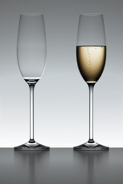 Full and empty champagne flute iover a gray background.