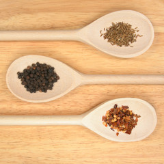 Wooden spoons with cooking ingredients on a wooden board