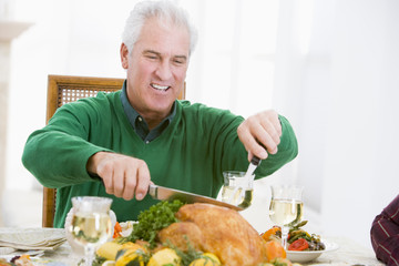 Man Carving Up Turkey At Christmas Dinner