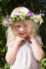 Obraz premium happy little girl in flowers wreath on green meadow