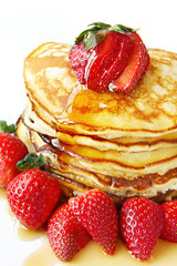 Stack of pancakes with fresh strawberries and maple syrup.