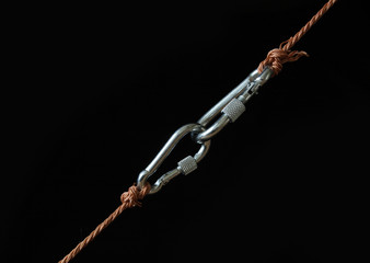 Fototapeta premium Two fastened clasps hanging with rope on black background