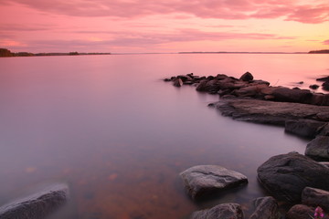 Obraz na płótnie Canvas Sunset by the lake, rocks, long exposure