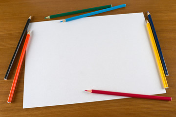 Blank paper sheet and crayons for drawing on desk