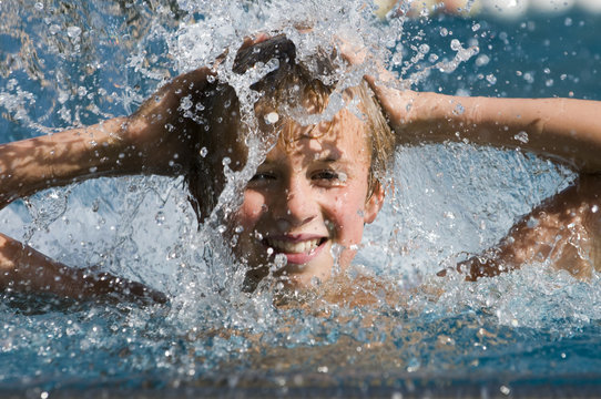 Portrait eines lachenden Jungen im Wasserschwall
