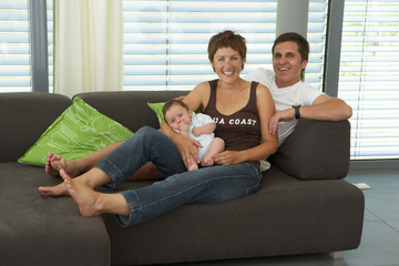 Obraz premium baby with parents on sofa at home