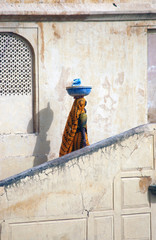 Mujer hindú subiendo escalera con vasija en la cabeza