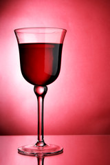 Glass of red wine close-up over red background