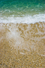 Wave on a pebbly sea shore background