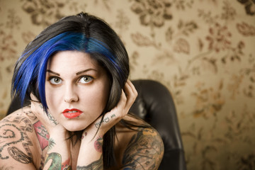 Pretty young woman with many tattoos in a leather chair