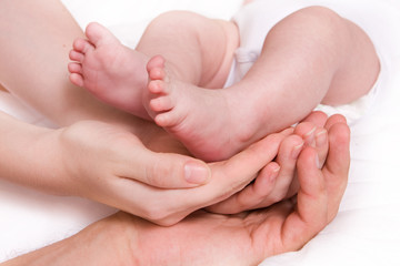 Little baby foots in hands of parents. Family concept