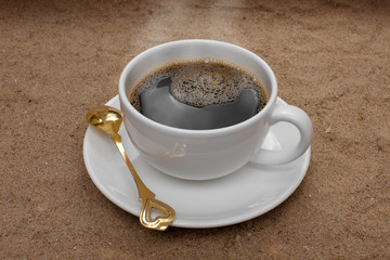 White coffee cup on sand