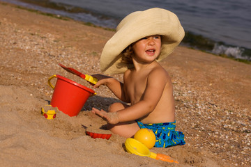 little girl in the bonnet plaing with sand, happy childhood