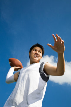 A Young Asian Football Player Throwing A Football