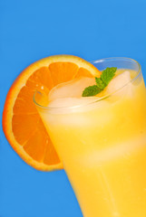 Frosty glass of orange juice with mint and ice