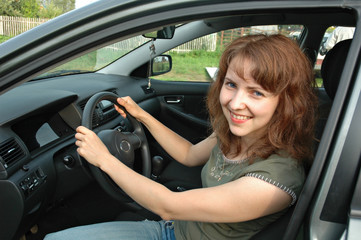 Obraz na płótnie Canvas The young girl without cosmetics smiles at the wheel the car