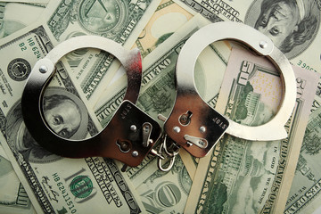 Silver handcuff and dollar bank notes
