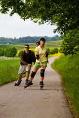 a couple ride rollerblades in the park