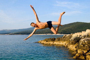 man jumping from rock in sea water and screaming aaaa