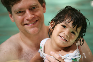 Father and toddler boy swimming in pool