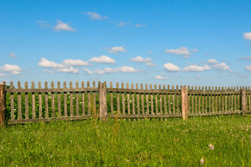 Fototapeta na wymiar Blue sky, green grass and fence