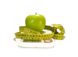 Green apple, scale and tape measure isolated