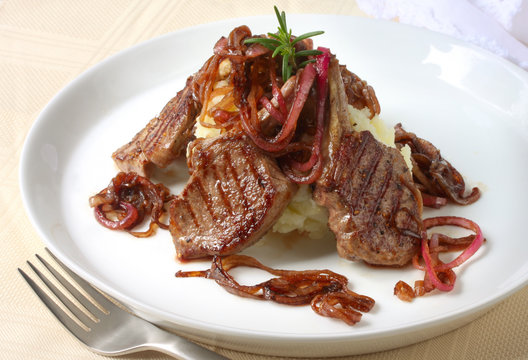 Grilled lamb cutlets over mashed potato, with red onion