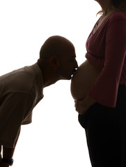 A soon to be father kisses the belly of his pregnant wife.